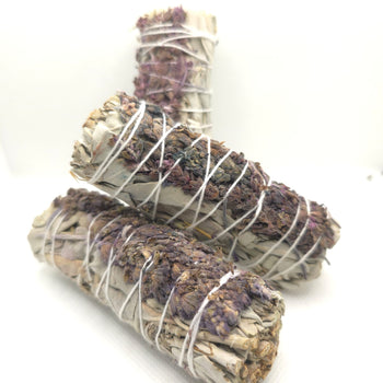Three bundles of sage wrapped in white twine on a white background